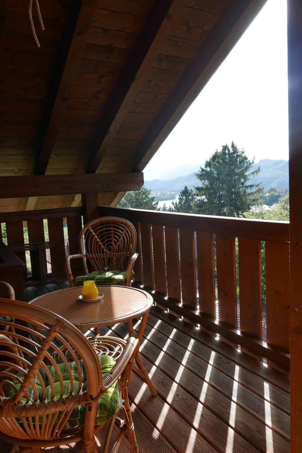 Balkon mit zwei Korbsesseln und kleinem Tisch, dahinter Bergblick