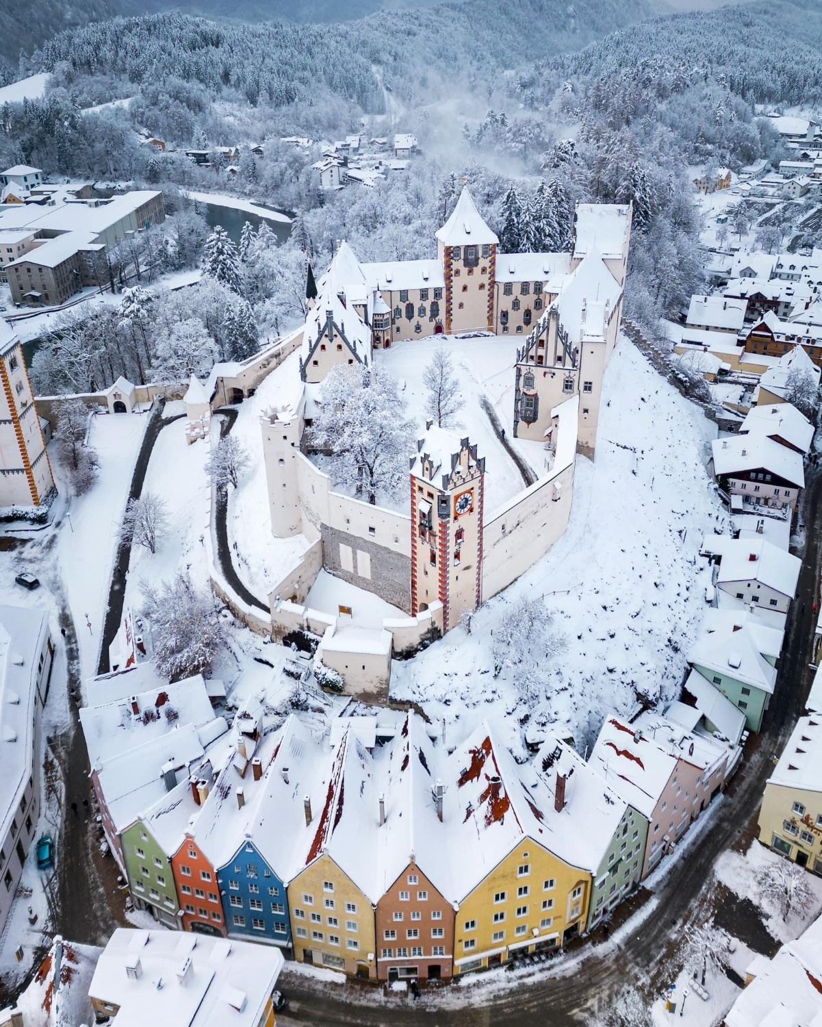 Das Hohe Schloss in Füssen im Schnee von oben, davor die bunten Häuser der Altstadt
