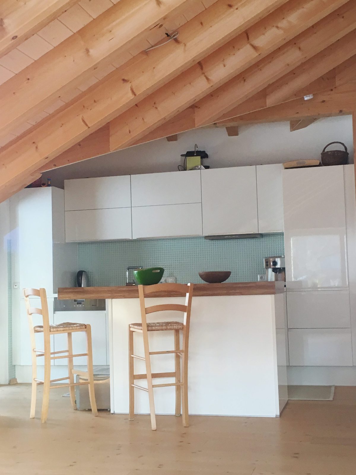 Weiße Küchenzeile mit Theke und zwei Holzhockern
