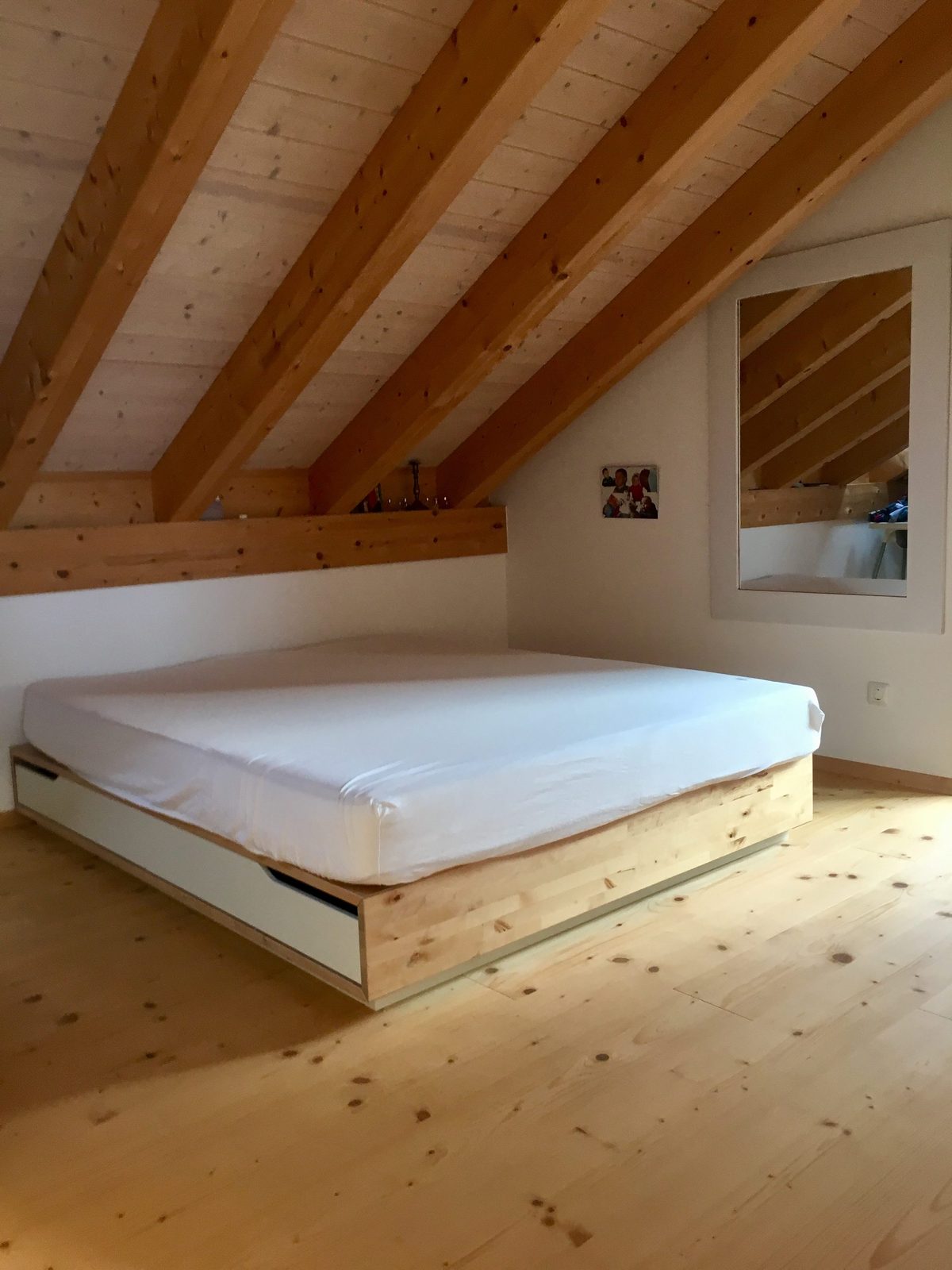 Schlafzimmer eins mit Doppelbett unter Dachschrägen aus Holz