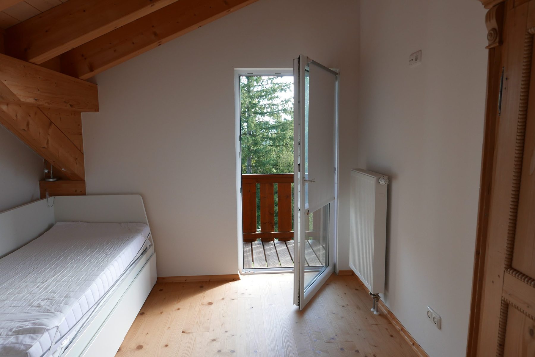 Schlafzimmer zwei, Blick vom Bett auf die Balkontür und Bäume