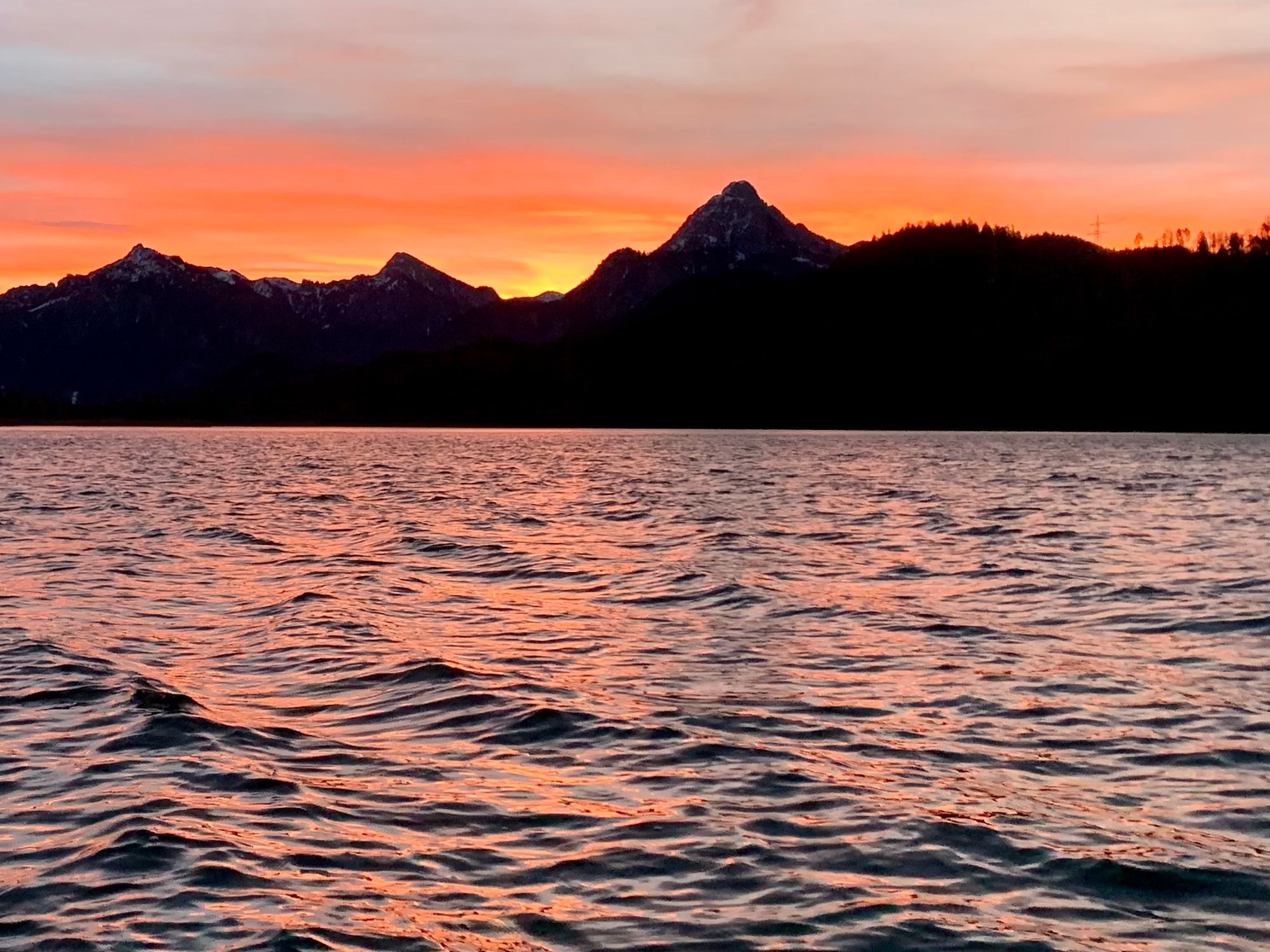 Sonnenuntergang über dem Weißensee, Bergsilhouetten vor orangem Himmel