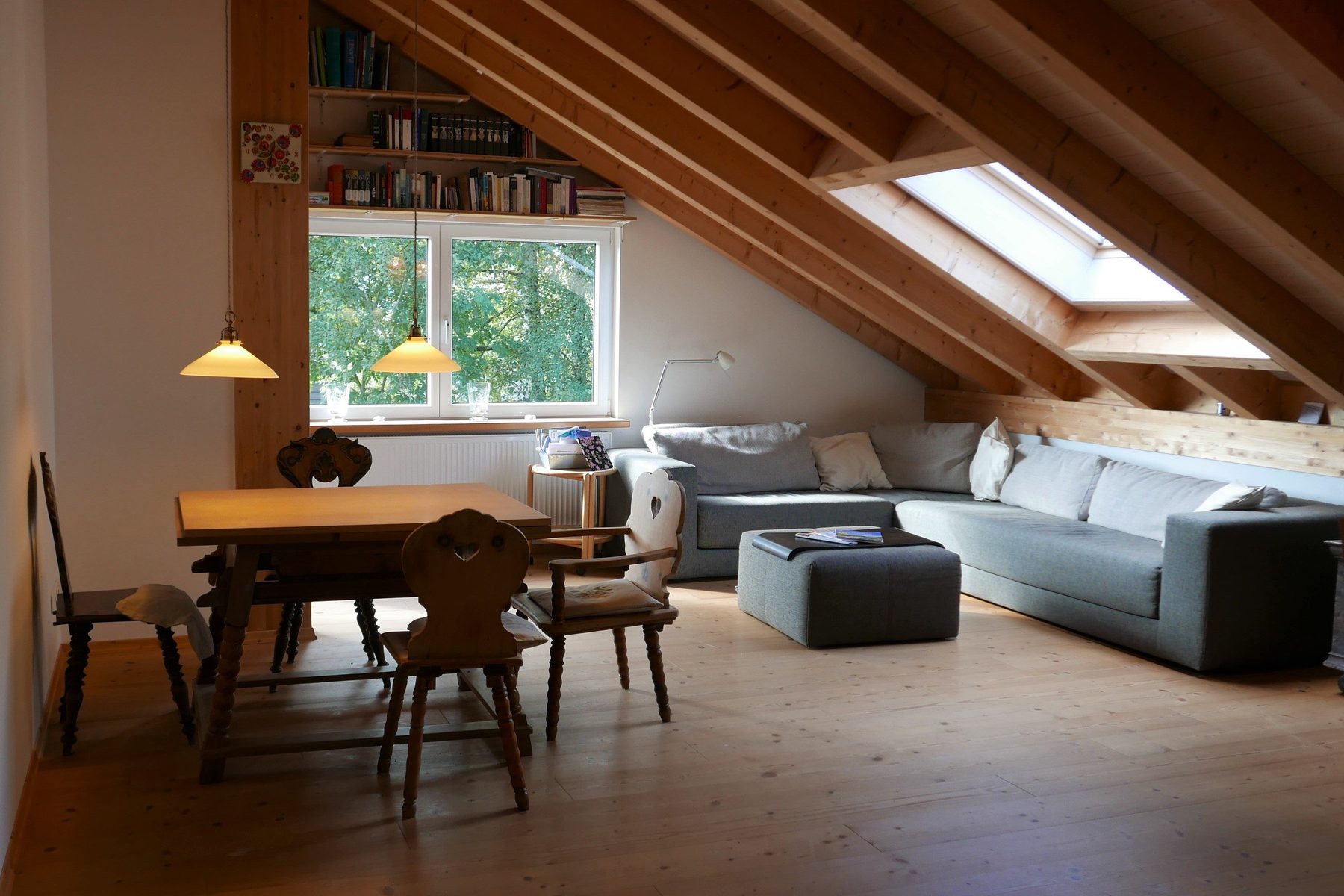 Wohnbereich mit Esstisch, Holzstühlen und Ecksofa vor dem Fenster
